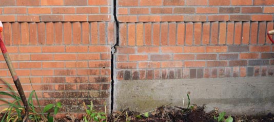 Vertical foundation crack in a brick wall showing structural settlement and foundation damage